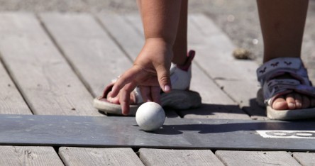 Närbild på barns hand som precis lagt golfbollen på plats för spel.