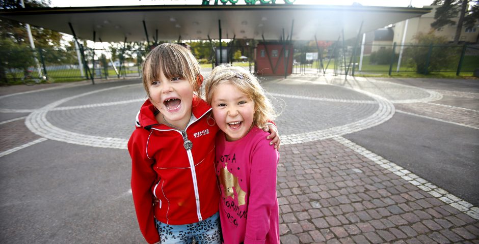 Två glada flickor framför huvudentrén till Mariebergsskogen.