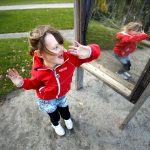 Flicka leker framför illusionsspegel i Lekträdgården. 