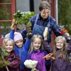 Trädgårdsmästare tillsammans med fyra flickor som stolt har skördat grönsaker i Barnens köksträdgård. 