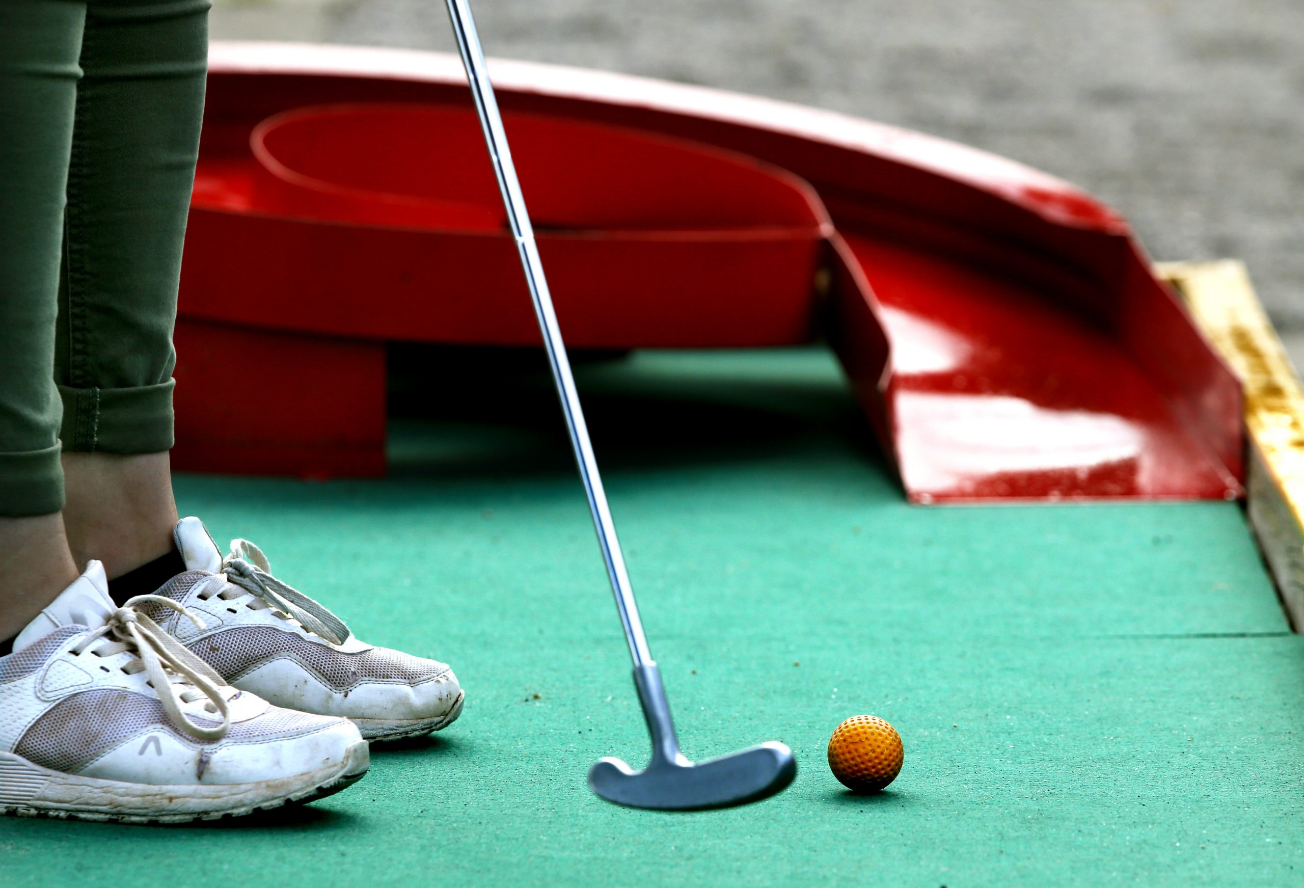 Närbild från minigolfen på golfklubba och boll, precis innan slag.
