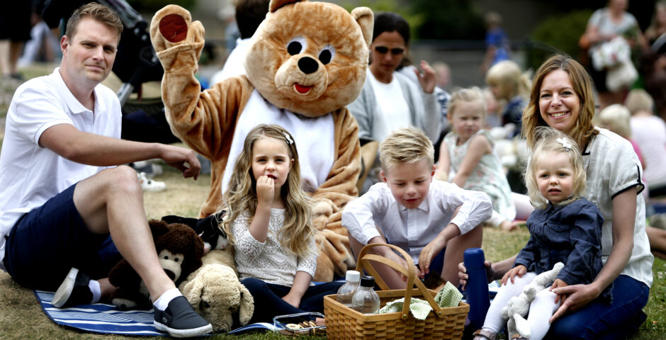 Familj har picknick med jättestort gosedjur.
