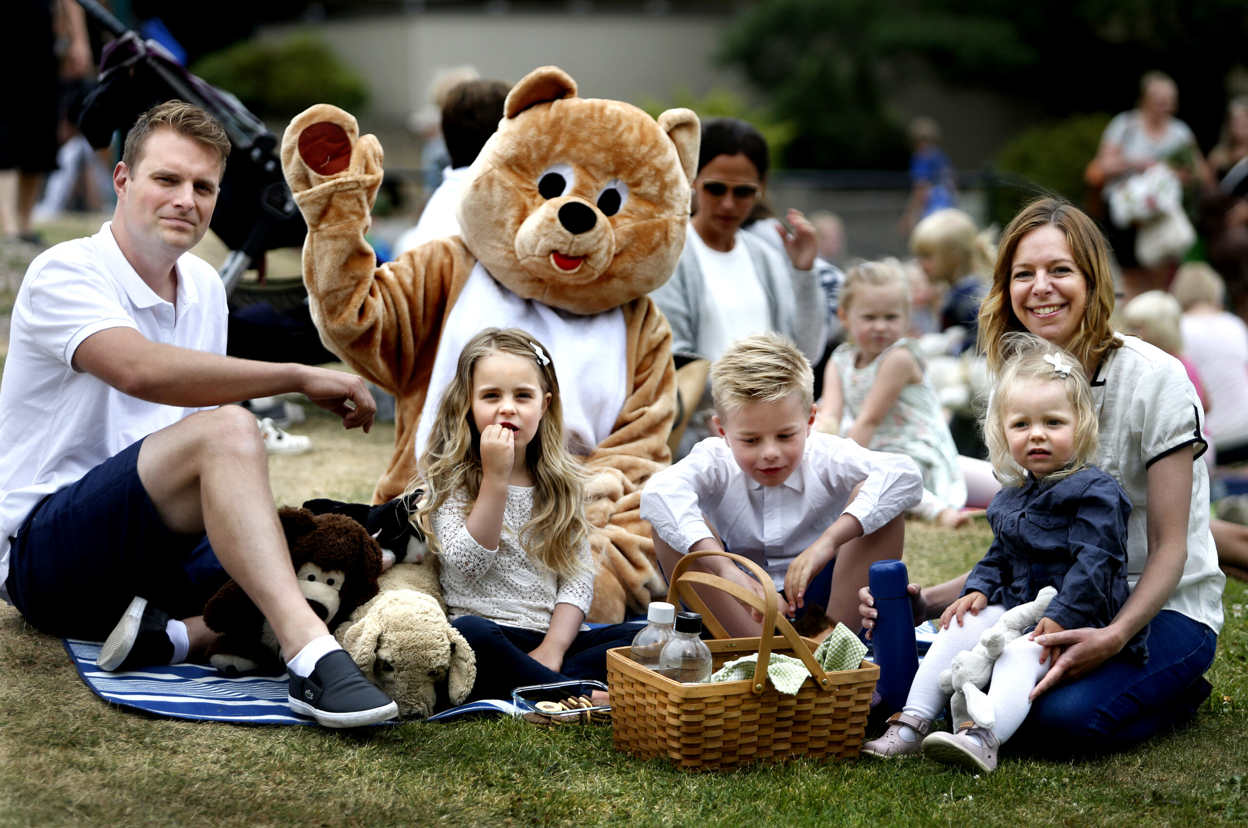Familj har picknick med jättestort gosedjur.